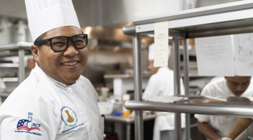 Male culinary student in kitchen smiling at camera