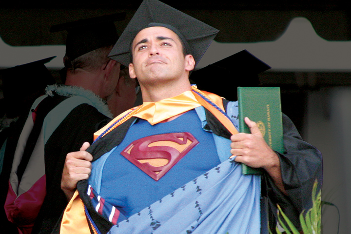 Male graduate opening graduation robe to reveal superman shirt underneath