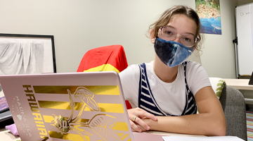 student with mask and laptop sitting at learning center