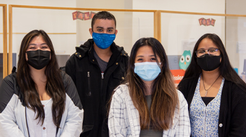four student workers from the Welcome Center posing for camera with masks on