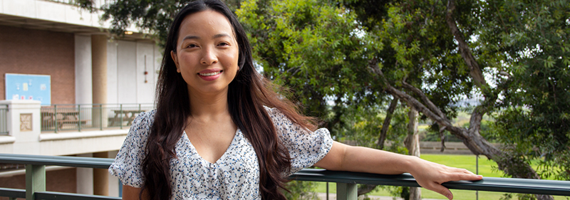 asian female outside campus building smiling at camera