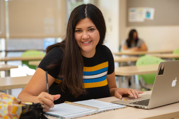 student writing in notebook and smiling