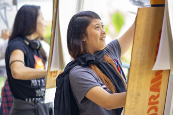 student drawing on large paper mounted on an upright easel