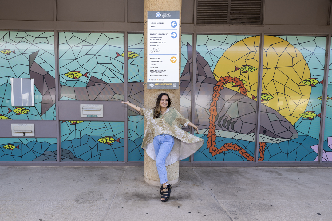 Taylor Wilson posing in front of Learning Commons window print