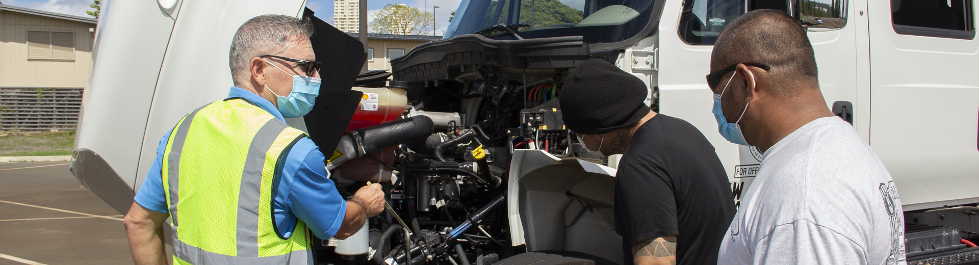 CDL instructor and students inspecting engine