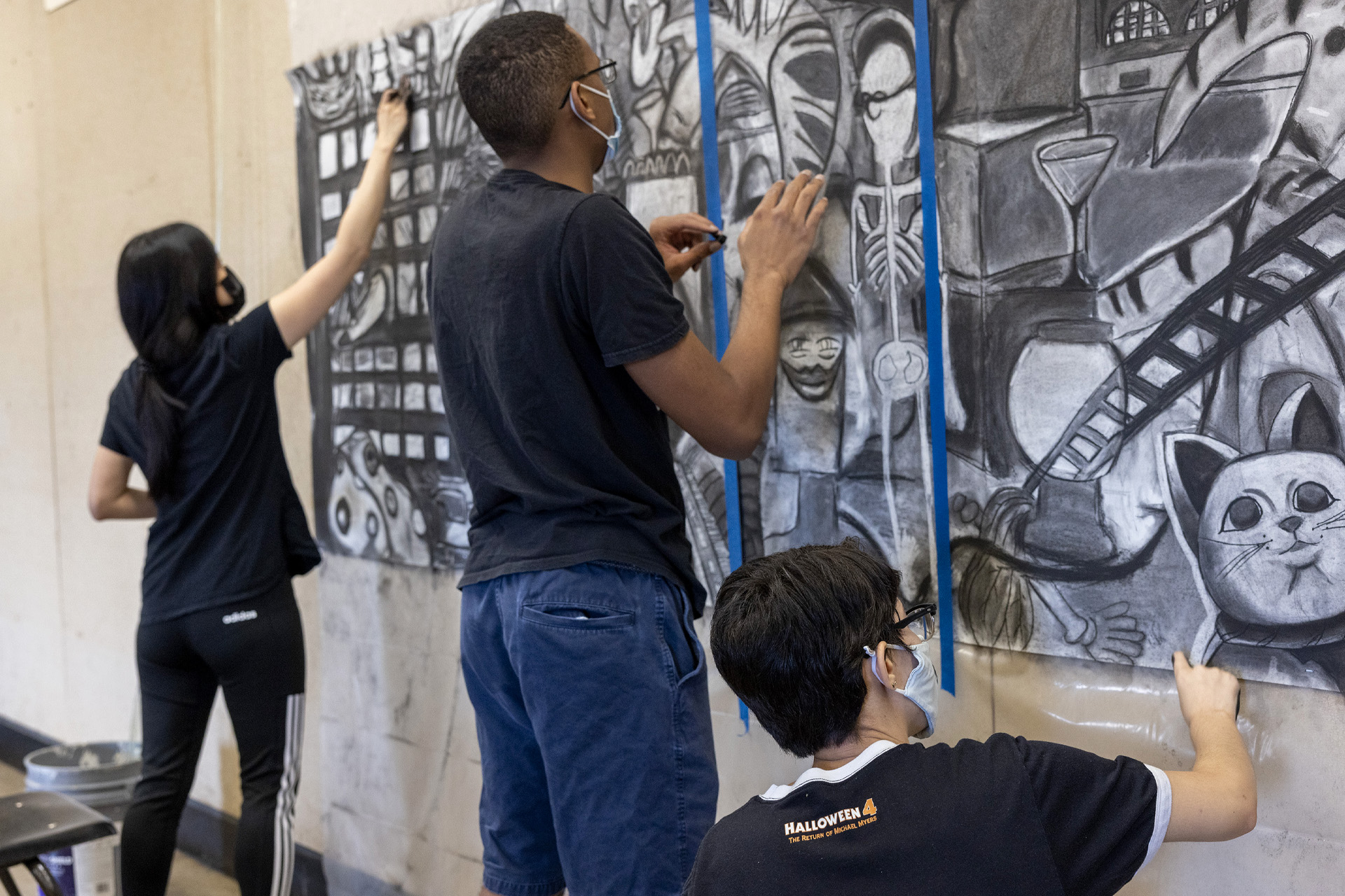 Three art students drawing on large scale mural