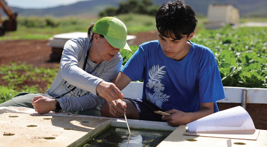 Instructor guiding student with aquaponics equipment in the field