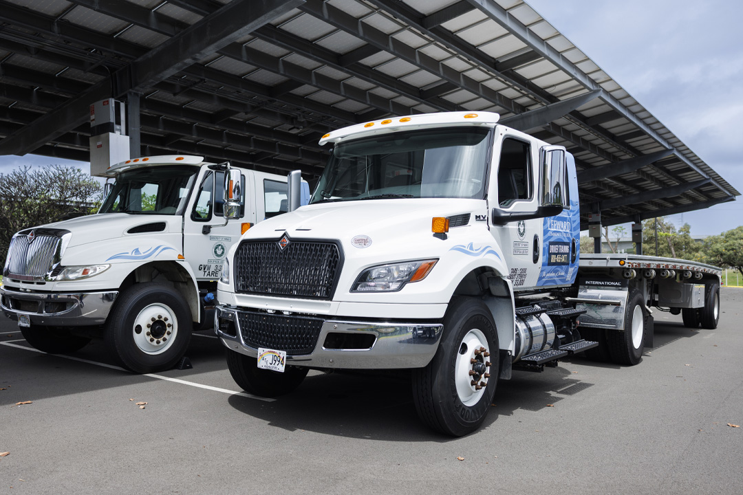 Two Leeward training tractor trailer trucks under solar pv canopy in parking lot